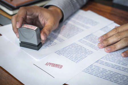 Hands of businessman stamp on paper document to approve business investment contract agreement.