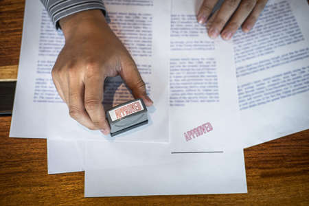Hands of businessman stamp on paper document to approve business investment contract agreement.