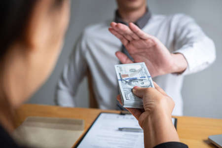 Anti bribery and corruption concept, Business man refusing and don't receive money banknote in envelope offer from business people to accept agreement contract of investment deal.の写真素材