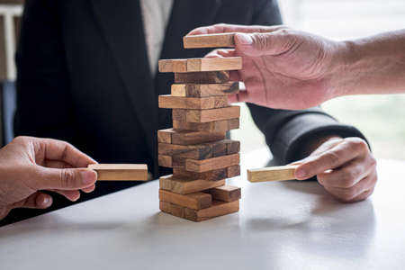 Alternative Risk and Strategy in Business, Hand of business team cooperative gambling placing making wooden block hierarchy on the tower to collaborative planning and development to successful.の写真素材