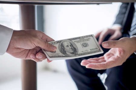 Dishonest cheating in business illegal money, Businessman receive bribe money under table to business people to give success the deal contract of investment, Bribery and corruption concept.の写真素材