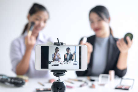 Business online on social media, Two Beautiful Woman Blogger is showing present tutorial beauty cosmetic product and broadcast live streaming video to social network while recording teaching online.の写真素材