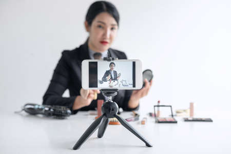 Business online on social media, Beautiful woman blogger is showing present tutorial beauty cosmetic product and broadcast live streaming video to social network while recording teaching online.の写真素材