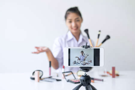 Business online on social media, Beautiful Asian woman blogger is showing present tutorial beauty cosmetic product and broadcast live streaming video to social network while recording teaching online.の写真素材