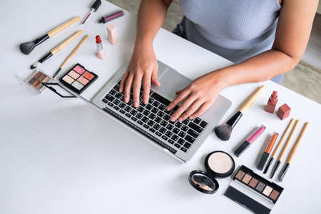 Business online on social media, Beautiful woman is watching online blogger tutorial on laptop, showing present tutorial beauty cosmetic using product makeup.の写真素材