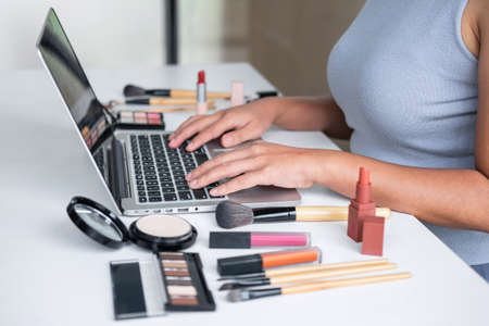 Business online on social media, Beautiful woman is watching online blogger tutorial on laptop, showing present tutorial beauty cosmetic using product makeup.の写真素材