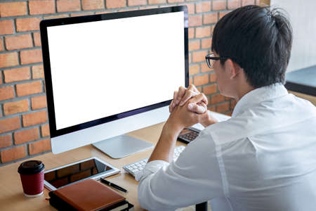 Image of Young man working in front of the computer laptop looking at screen with a clean white screen and blank space for text in modern workspace.の写真素材
