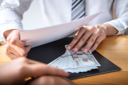 Dishonest cheating in business illegal money, Businessman giving bribe money in business people to give success the deal contract of investment, Bribery and corruption concept.の写真素材