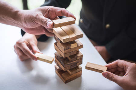 Alternative Risk and Strategy in Business, Hand of business team cooperative gambling placing making wooden block hierarchy on the tower to collaborative planning and development to successful.の写真素材