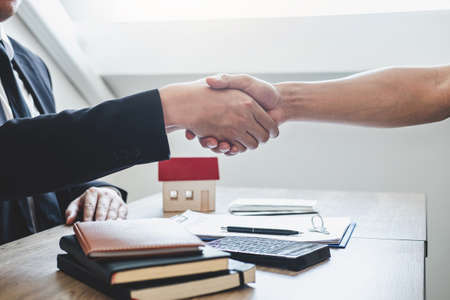 Finishing to successful deal of real estate, Broker and client shaking hands after signing contract approved application form, concerning mortgage loan offer for and house insurance.の写真素材