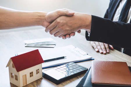 Finishing to successful deal of real estate, Broker and client shaking hands after signing contract approved application form, concerning mortgage loan offer for and house insurance.の写真素材
