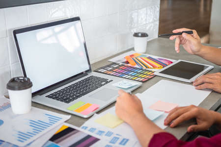 Teamwork of creative designers working on new project and choose color swatch samples for selection coloring on digital graphic tablet with work tools and equipment at workplace.の写真素材