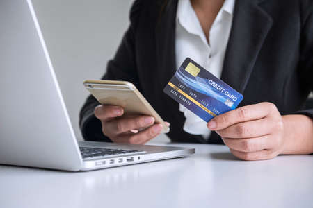 Young woman consumer holding smartphone, credit card and typing on laptop for online shopping and payment make a purchase on the Internet, Online payment, networking and buy product technology.の写真素材