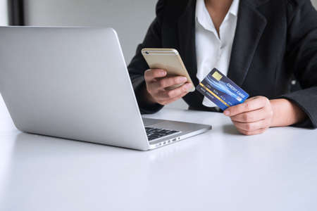 Young woman consumer holding smartphone, credit card and typing on laptop for online shopping and payment make a purchase on the Internet, Online payment, networking and buy product technology.の写真素材