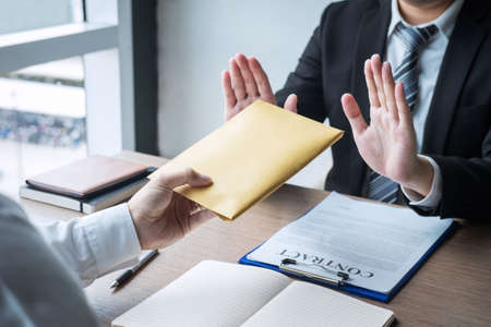 Anti bribery and corruption concept, Business man refusing and don't receive money banknote in envelope offer from business people to accept agreement contract of investment deal.の写真素材