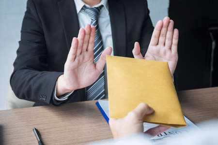 Anti bribery and corruption concept, Business man refusing and don't receive money banknote in envelope offer from business people to accept agreement contract of investment deal.の写真素材