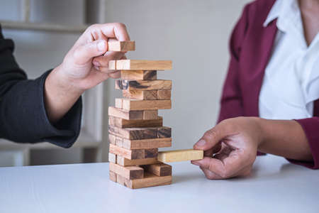 Alternative Risk and Strategy in Business, Hand of business team cooperative gambling placing making wooden block hierarchy on the tower to collaborative planning and development to successful.の写真素材