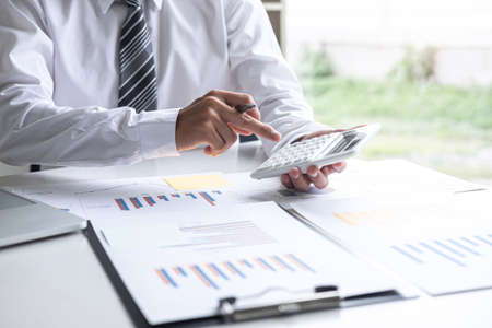 Businessman accountant working analyzing and calculating expense annual financial report balance sheet statement, doing finance making notes on report, Financing Accounting Banking Concept.の写真素材