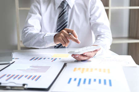 Businessman accountant working analyzing and calculating expense annual financial report balance sheet statement, doing finance making notes on report, Financing Accounting Banking Concept.の写真素材