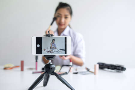 Business online on social media, Beautiful Asian woman blogger is showing present tutorial beauty cosmetic product and broadcast live streaming video to social network while recording teaching online.の写真素材
