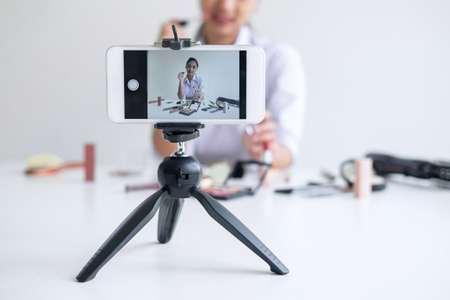 Business online on social media, Beautiful Asian woman blogger is showing present tutorial beauty cosmetic product and broadcast live streaming video to social network while recording teaching online.の写真素材