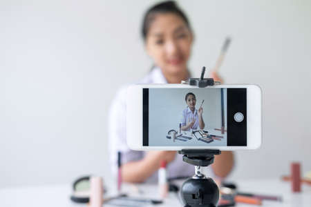Business online on social media, Beautiful Asian woman blogger is showing present tutorial beauty cosmetic product and broadcast live streaming video to social network while recording teaching online.の写真素材