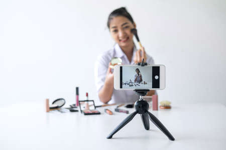 Business online on social media, Beautiful Asian woman blogger is showing present tutorial beauty cosmetic product and broadcast live streaming video to social network while recording teaching online.の写真素材