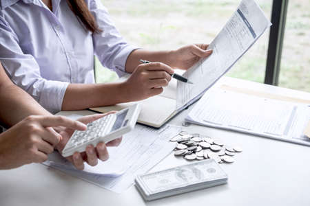 Images of Husband and wife using calculator to calculating expenditure receipt bills of various activity cost and expenses in home office and written make report to plan of spent in future.の写真素材