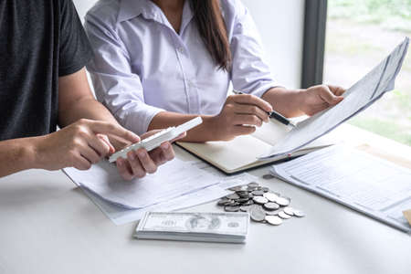 Images of Husband and wife using calculator to calculating expenditure receipt bills of various activity cost and expenses in home office and written make report to plan of spent in future.の写真素材