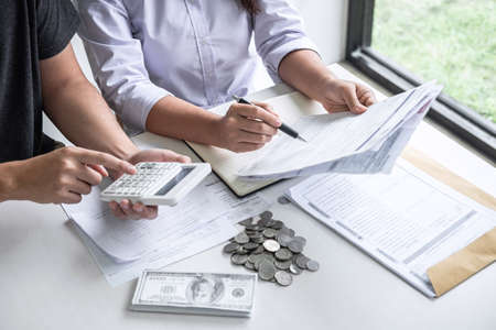 Images of Husband and wife using calculator to calculating expenditure receipt bills of various activity cost and expenses in home office and written make report to plan of spent in future.の写真素材
