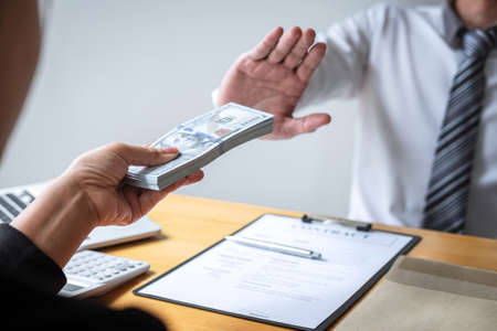 Anti bribery and corruption concept, Business man refusing and don't receive money banknote in envelope offer from business people to accept agreement contract of investment deal.の写真素材