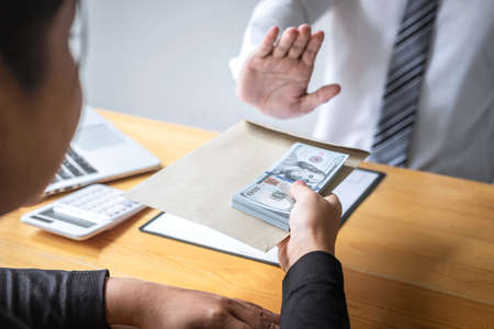Anti bribery and corruption concept, Business man refusing and don't receive money banknote in envelope offer from business people to accept agreement contract of investment deal.の写真素材