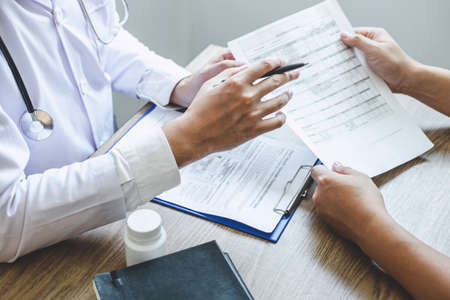 Professional doctor in white uniform gown coat and patient discussing consults to treatment of symptom disease and making prescriptions.の写真素材