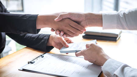 Dishonest cheating in business illegal money, Businessman handshake with money of dollar banknotes in hands from while give success the deal, Bribery and corruption concept.の写真素材