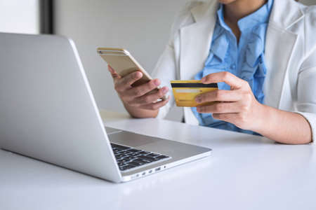Young woman consumer holding smartphone, credit card and typing on laptop for online shopping and payment make a purchase on the Internet, Online payment, networking and buy product technology.の写真素材
