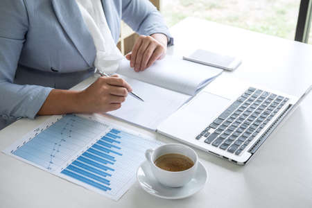 Business woman accountant financier working audit and calculating expense financial annual report balance sheet statement, doing finance checking document and making notes on report paper.の写真素材
