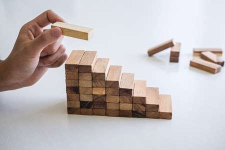 Alternative Risk and Strategy in business to make growth, Image of Business man's hand placing making a wooden block stacking hierarchy on growing to lay the foundation and development to successful.の写真素材