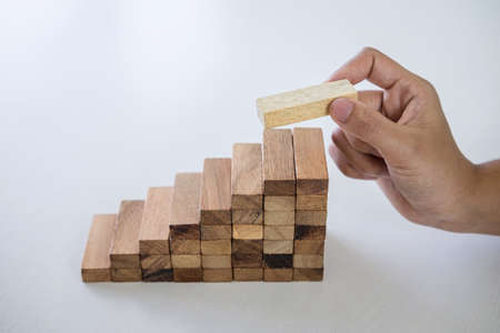 Alternative Risk and Strategy in business to make growth, Image of Business man's hand placing making a wooden block stacking hierarchy on growing to lay the foundation and development to successful.の写真素材