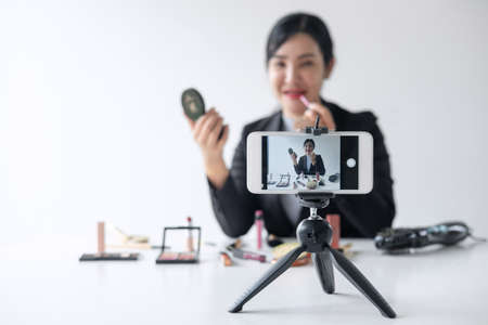 Business online on social media, Beautiful woman blogger is showing present tutorial beauty cosmetic product and broadcast live streaming video to social network while recording teaching online.の写真素材