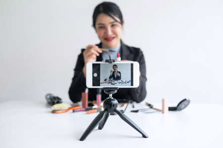 Business online on social media, Beautiful woman blogger is showing present tutorial beauty cosmetic product and broadcast live streaming video to social network while recording teaching online.の写真素材