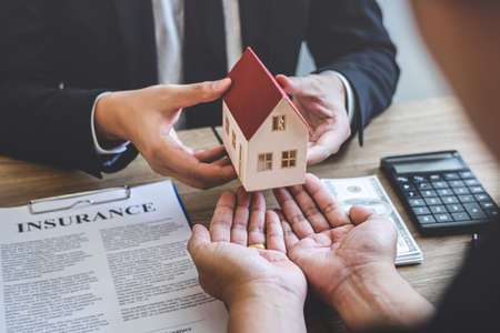 Estate agent giving house and keys to client after signing agreement contract real estate with approved mortgage application form, concerning mortgage loan offer for and house insurance.の写真素材