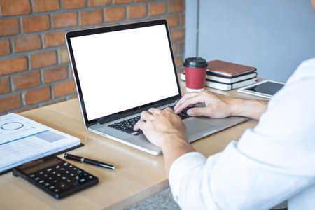 Image of Young man working in front of the laptop looking at screen with a clean white screen and blank space for text and hand typing information on keyboard in modern workspace.の写真素材