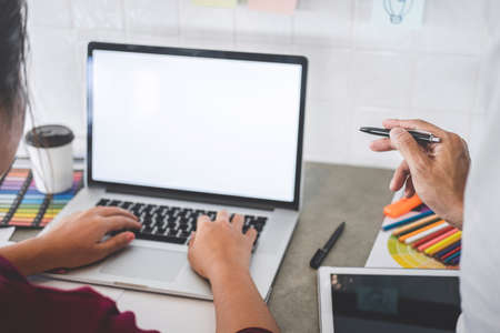 Teamwork of creative designers working on new project and choose color swatch samples for selection coloring on digital graphic tablet with work tools and equipment at workplace.の写真素材