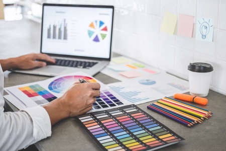 Young creative graphic designer working on project architectural drawing and color swatches,...
