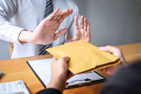 Anti bribery and corruption concept, Business man refusing and don't receive money banknote in envelope offer from business people to accept agreement contract of investment deal.の写真素材