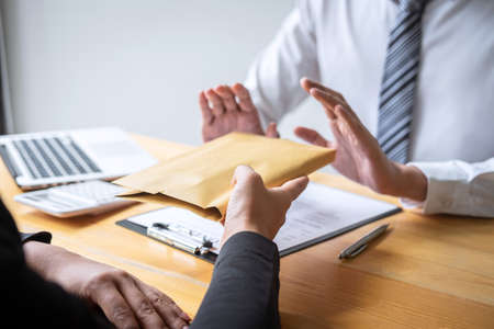 Anti bribery and corruption concept, Business man refusing and don't receive money banknote in envelope offer from business people to accept agreement contract of investment deal.の写真素材
