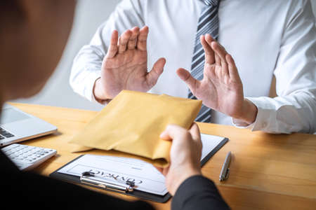 Anti bribery and corruption concept, Business man refusing and don't receive money banknote in envelope offer from business people to accept agreement contract of investment deal.の写真素材