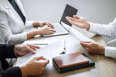 Employer or committee holding reading a resume with talking during about his profile of candidate, employer in suit is conducting a job interview, manager resource employment and recruitment concept.の写真素材