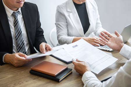 Employer or committee holding reading a resume with talking during about his profile of candidate, employer in suit is conducting a job interview, manager resource employment and recruitment concept.の写真素材