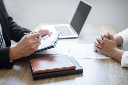 Employer or committee holding reading a resume with talking during about his profile of candidate, employer in suit is conducting a job interview, manager resource employment and recruitment concept.の写真素材